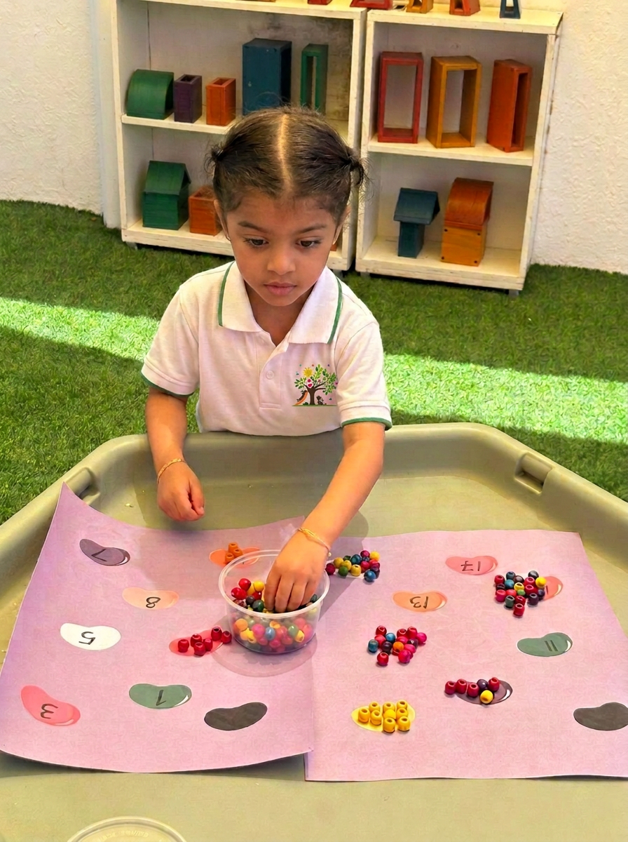 A child counting beads on a tray in the outdoor area