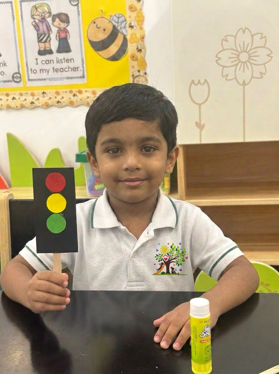 A child proudly holding a handmade traffic light craft